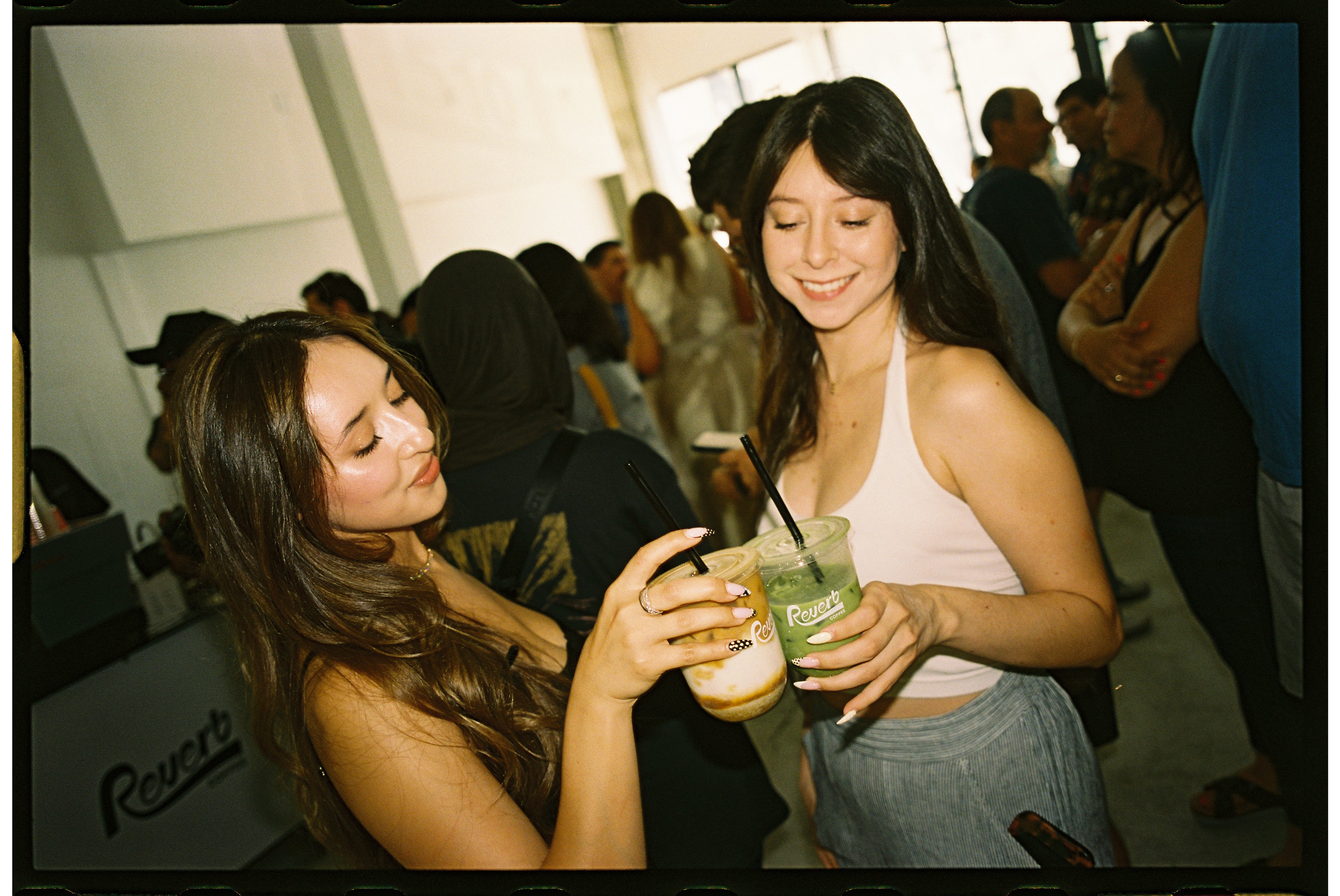 Two people drinking an iced latte and iced matcha at an event